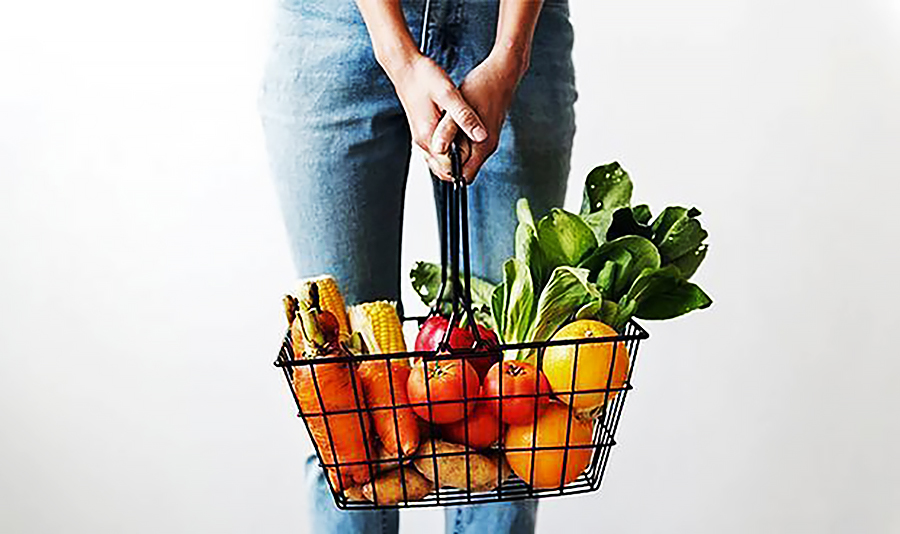 Nainen-kannattelee-vihanneksia-sisaltavaa-ruokakoria