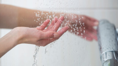 Kädet suihkussa vesihanan alla.