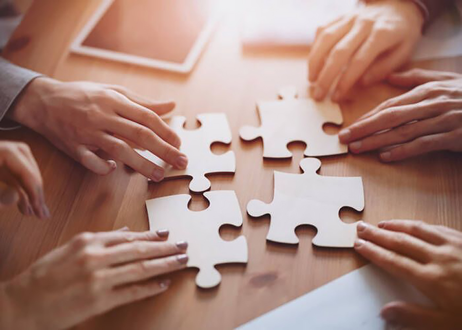 Kädet ja palapelin palat pöydällä