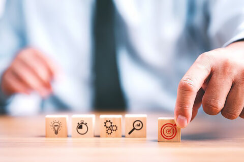 Mies asettelee pöydällä riviin viittä puukuutiota