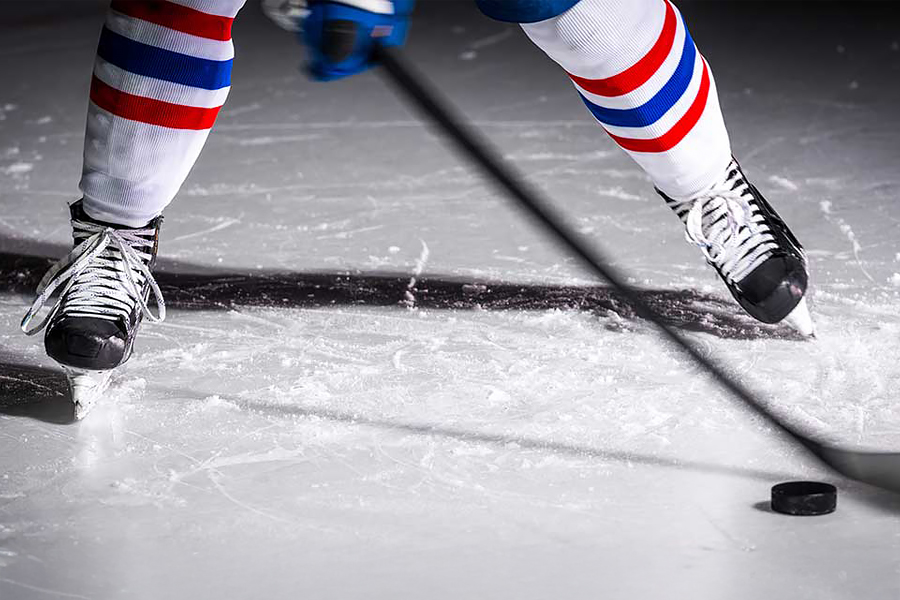 Jääkiekkoilija kaukalossa kiekon kanssa