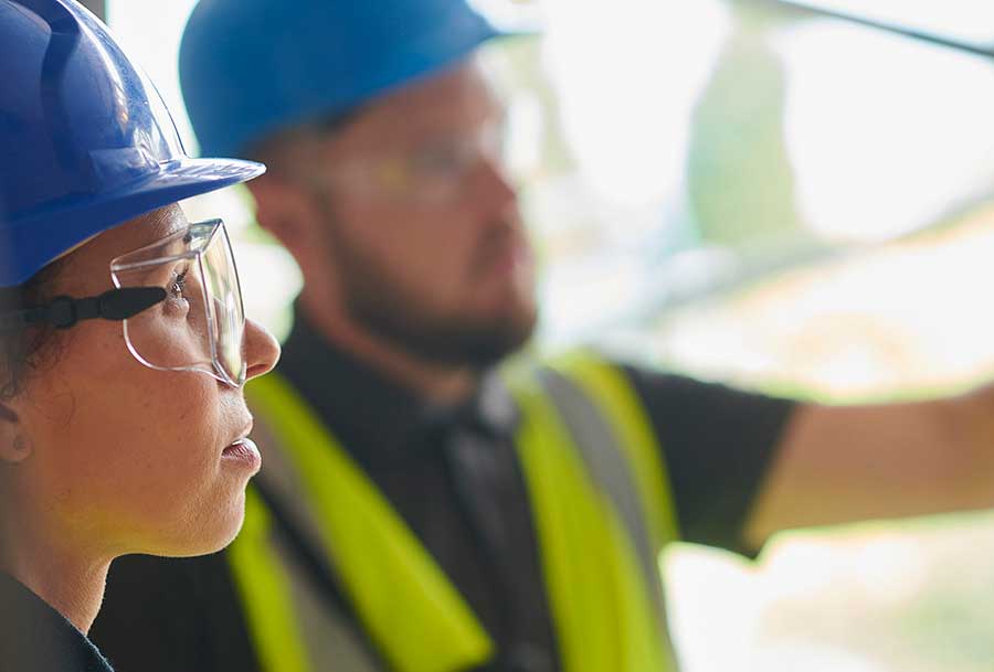 Nainen ja mies huomioliiveissä ja kypärä päässä